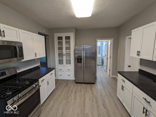 kitchen featuring light hardwood / wood-style flooring, white cabinets, a textured ceiling, and appliances with stainless steel finishes