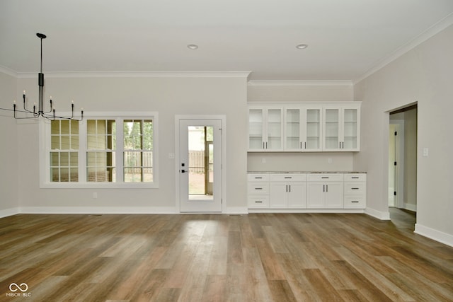 unfurnished living room with a chandelier, light hardwood / wood-style flooring, and ornamental molding