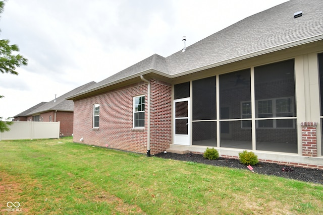 back of property with a sunroom and a yard