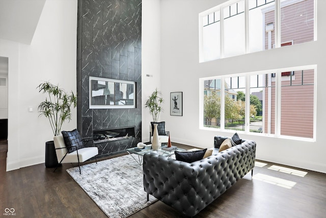 living room featuring dark hardwood / wood-style flooring, a premium fireplace, and a high ceiling