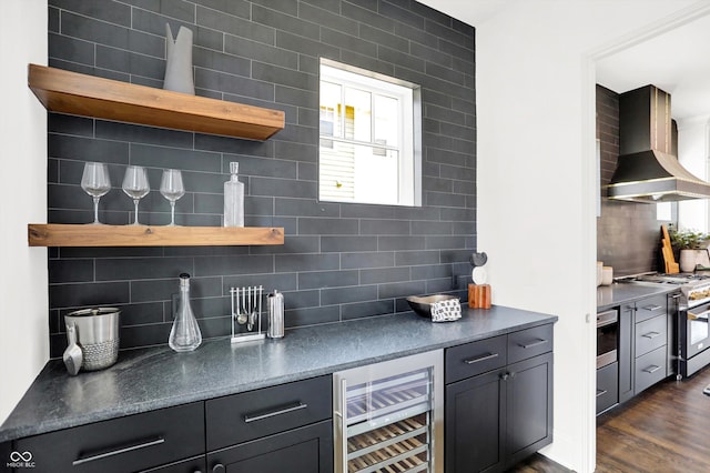 kitchen with appliances with stainless steel finishes, beverage cooler, decorative backsplash, exhaust hood, and dark wood-type flooring