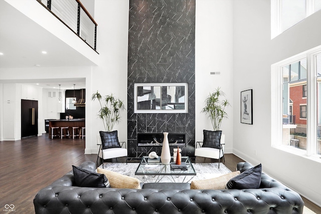 living room with a high ceiling, plenty of natural light, dark hardwood / wood-style floors, and a fireplace