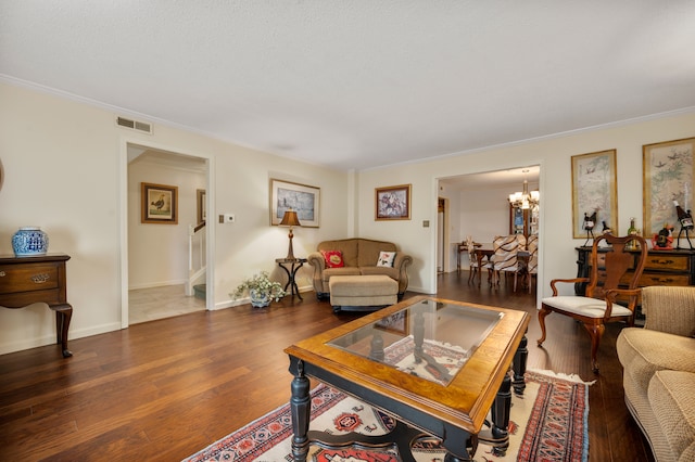 living room featuring ornamental molding, dark hardwood / wood-style floors, and a notable chandelier