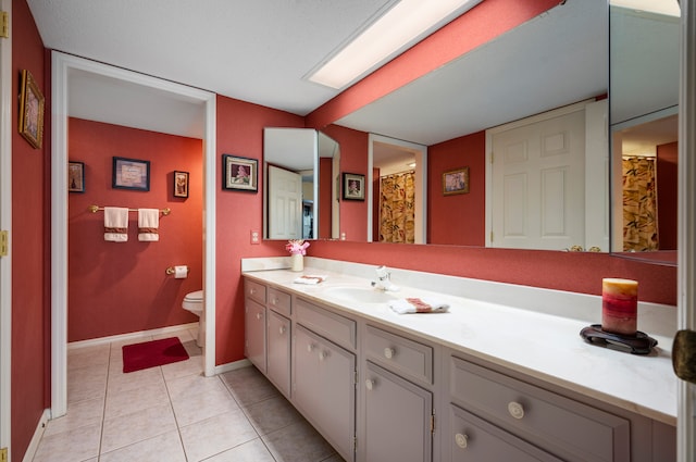 bathroom with tile patterned flooring, vanity, toilet, and a textured ceiling