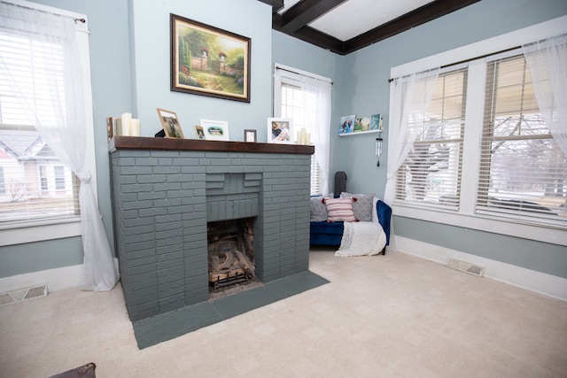 carpeted living room with a fireplace and beam ceiling