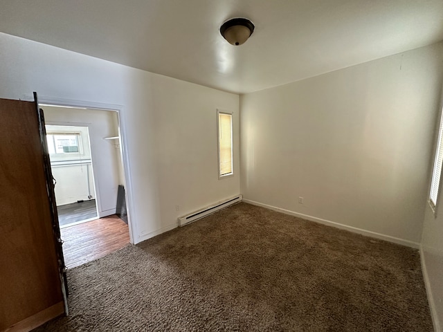 empty room with a baseboard radiator and dark colored carpet