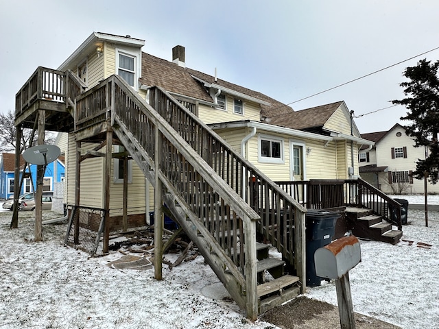 snow covered rear of property with a wooden deck