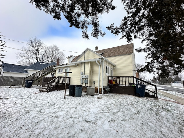 snow covered property with central AC and a wooden deck