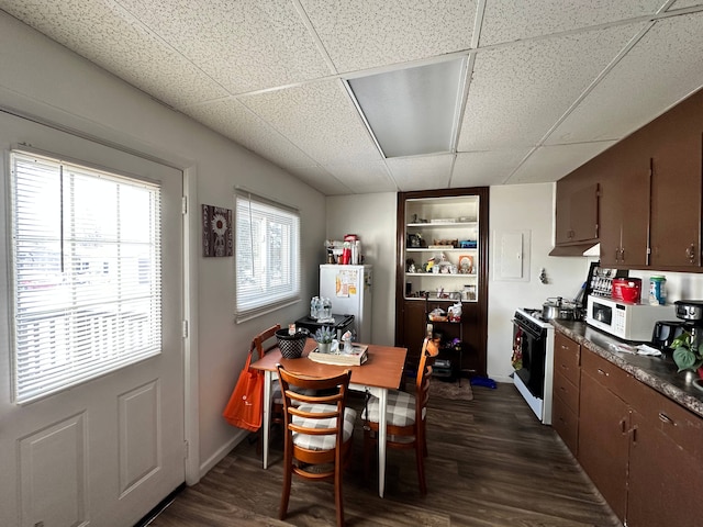 dining area featuring built in shelves, a paneled ceiling, and dark wood-type flooring