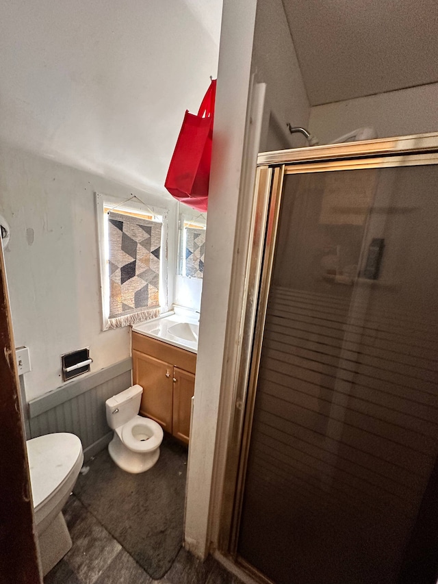 bathroom featuring tile floors, toilet, vanity, and a shower with shower door