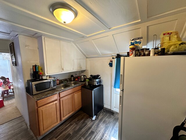 kitchen with sink, white fridge, dark wood-type flooring, and vaulted ceiling