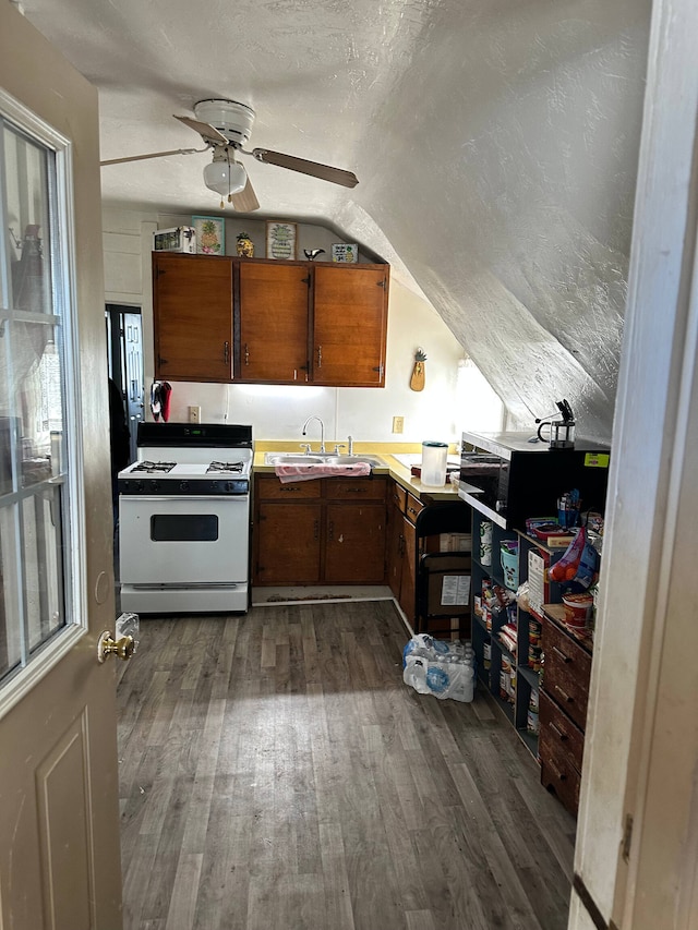 kitchen featuring dark wood-type flooring, ceiling fan, vaulted ceiling, sink, and white range with gas cooktop