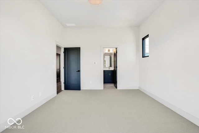 unfurnished bedroom with ensuite bathroom and light carpet