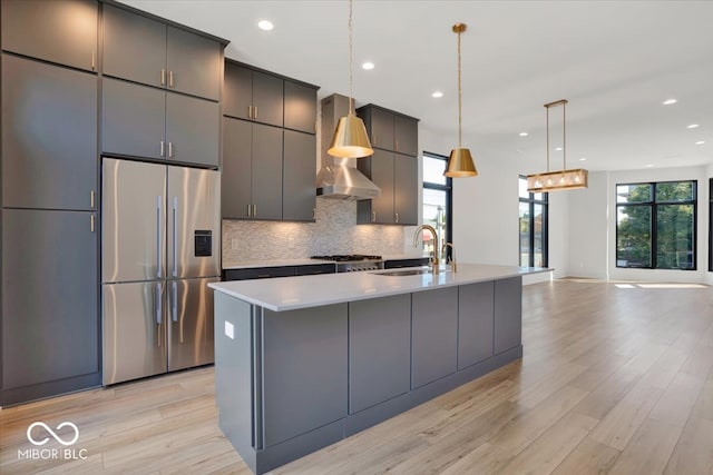 kitchen with gray cabinets, pendant lighting, light wood-type flooring, an island with sink, and stainless steel fridge with ice dispenser