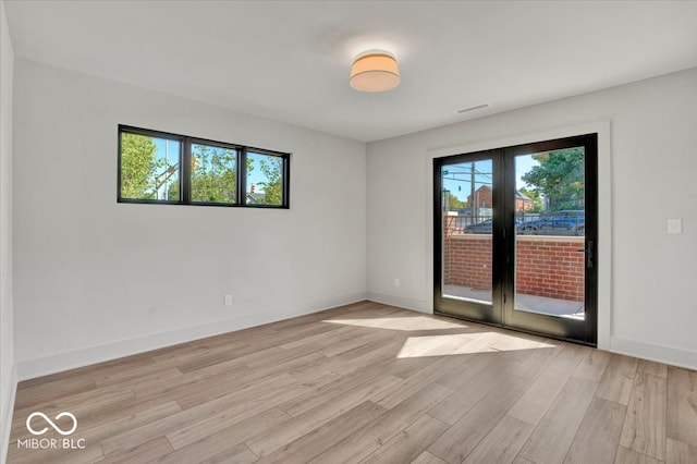 empty room with french doors and light hardwood / wood-style flooring