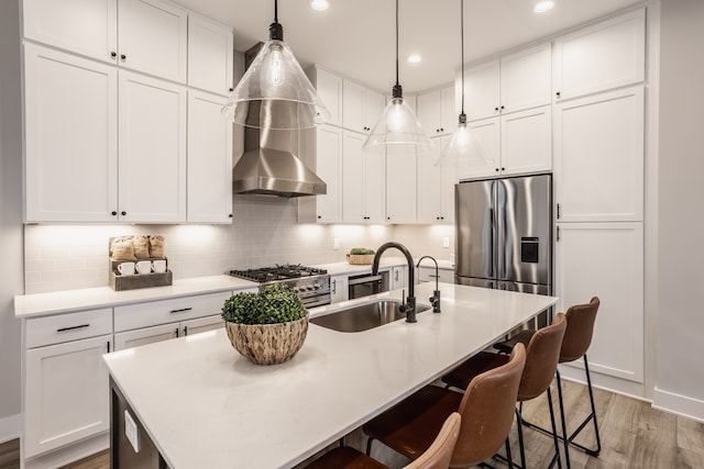 kitchen with hardwood / wood-style floors, an island with sink, stainless steel appliances, backsplash, and white cabinets