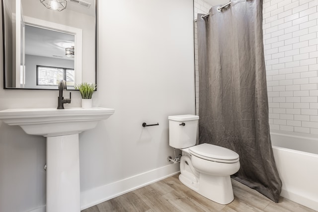 bathroom with wood-type flooring, toilet, and shower / tub combo