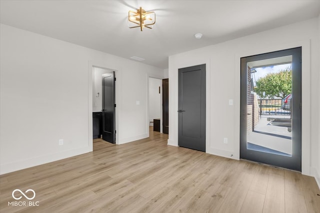 doorway to outside with a notable chandelier and light hardwood / wood-style floors