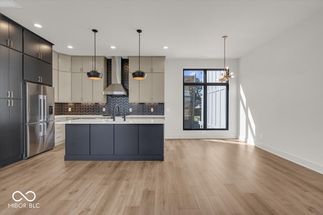 kitchen featuring wall chimney range hood, stainless steel fridge, pendant lighting, and light hardwood / wood-style flooring