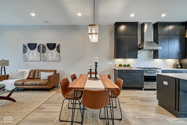 kitchen with visible vents, hanging light fixtures, light countertops, high end stainless steel range oven, and wall chimney range hood