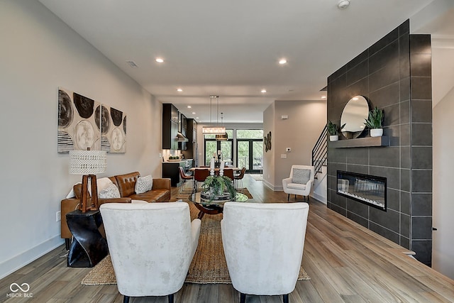 dining space with a tile fireplace, baseboards, light wood finished floors, and recessed lighting