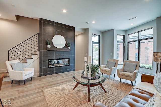 living room featuring recessed lighting, a fireplace, visible vents, stairway, and light wood-type flooring