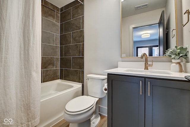 bathroom featuring visible vents, toilet, shower / bath combo, vanity, and wood finished floors