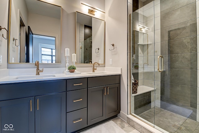 bathroom with double vanity, marble finish floor, a shower stall, and a sink