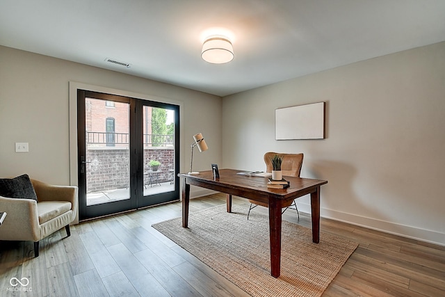 office with french doors, visible vents, baseboards, and wood finished floors