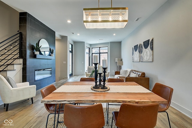 dining area with baseboards, visible vents, a tiled fireplace, light wood-type flooring, and recessed lighting