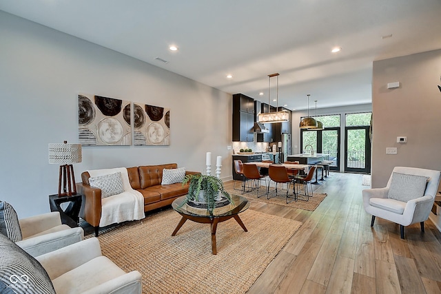 living room featuring baseboards, recessed lighting, visible vents, and light wood-style floors