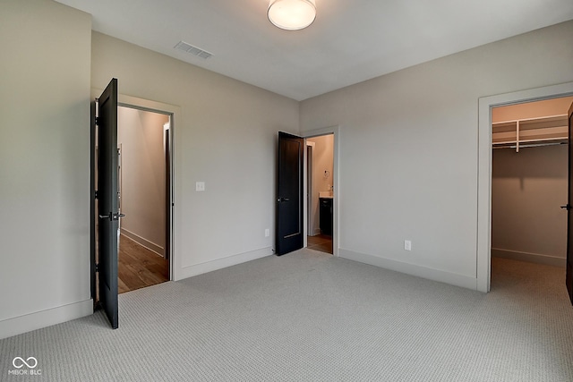 unfurnished bedroom with visible vents, baseboards, carpet, a walk in closet, and a closet