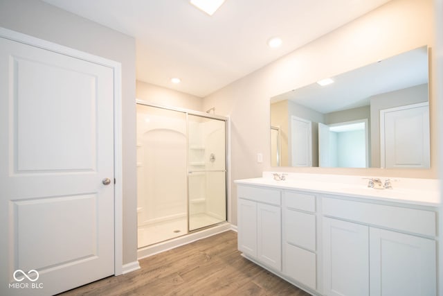 bathroom featuring hardwood / wood-style floors, walk in shower, dual sinks, and oversized vanity