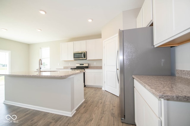 kitchen featuring light stone counters, stainless steel appliances, wood-type flooring, white cabinets, and sink