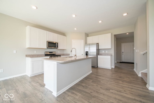 kitchen featuring light hardwood / wood-style flooring, an island with sink, stainless steel appliances, sink, and white cabinets