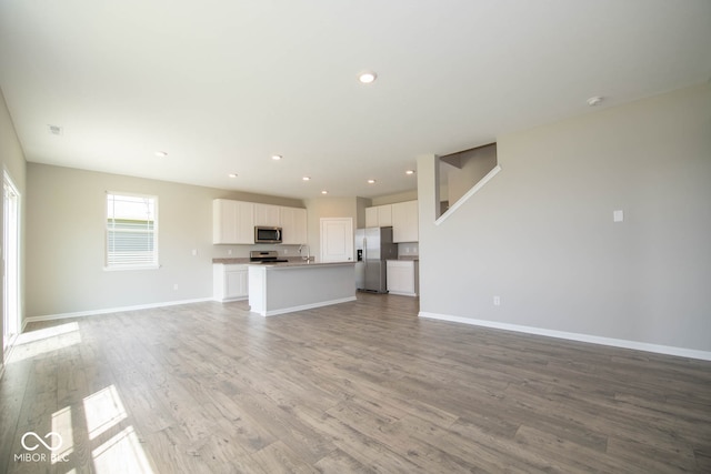 unfurnished living room featuring sink and light hardwood / wood-style floors