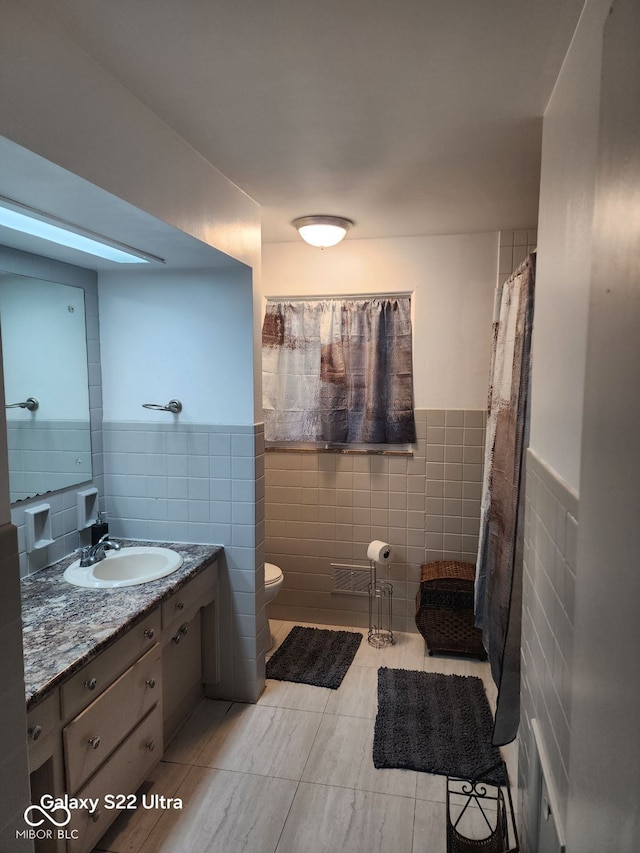 bathroom with tile patterned floors, vanity, tile walls, and toilet