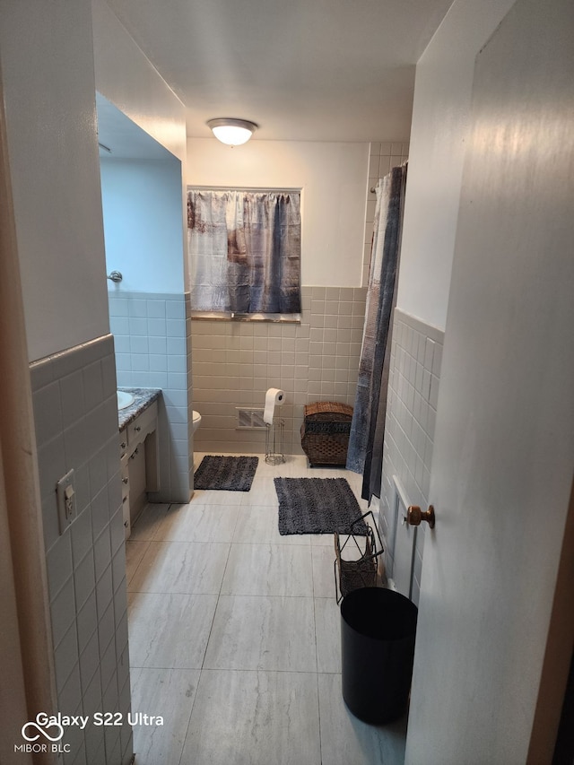 bathroom with tile patterned flooring, vanity, toilet, and tile walls