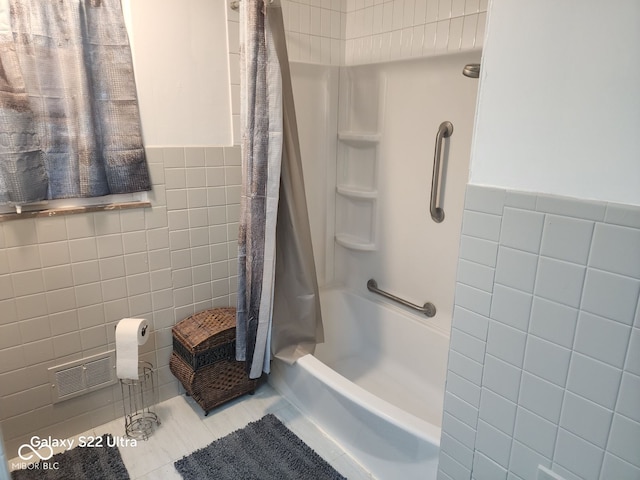 bathroom featuring tile patterned flooring, shower / bath combination with curtain, and tile walls