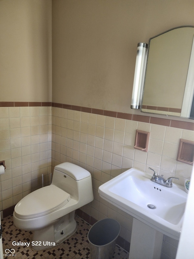 bathroom with sink, tile patterned flooring, tile walls, and toilet