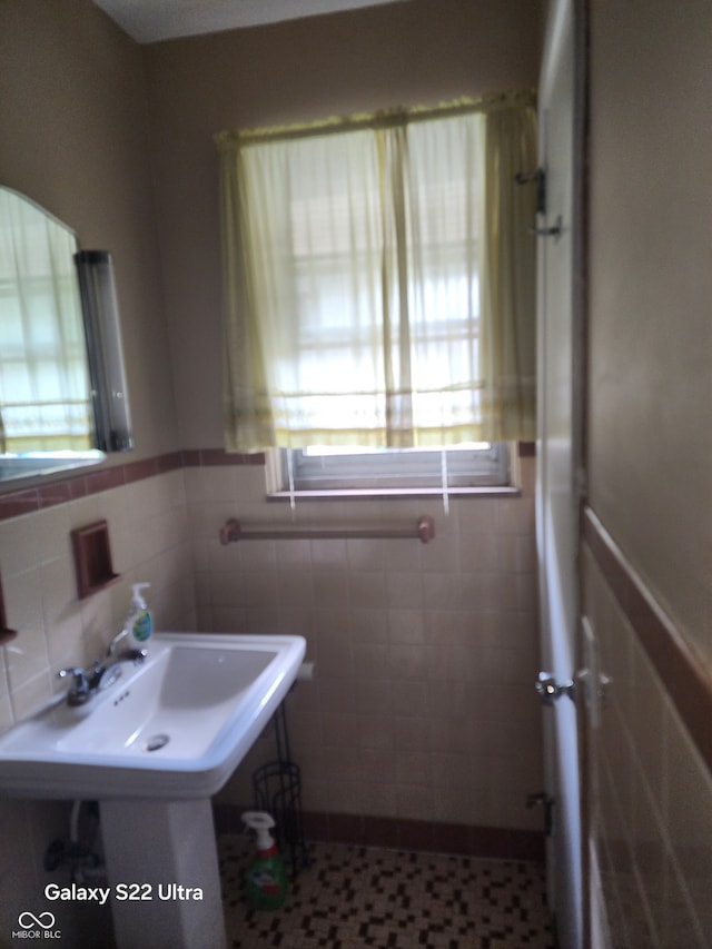 bathroom with sink, a healthy amount of sunlight, and tile walls