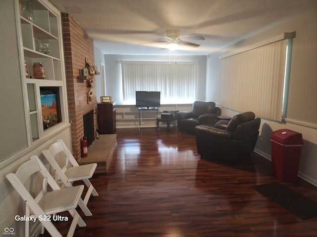 living room featuring a fireplace, ceiling fan, and dark wood-type flooring