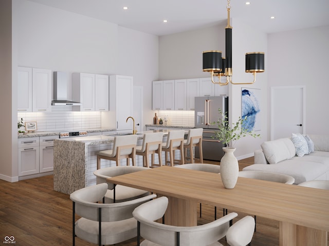 dining space with sink, dark wood-type flooring, a chandelier, and a high ceiling