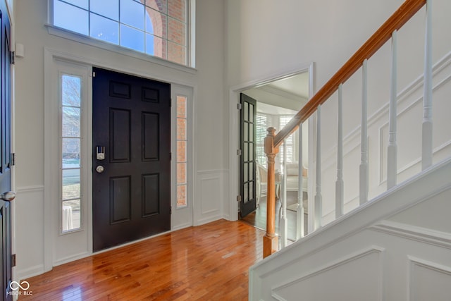 foyer featuring a high ceiling, a healthy amount of sunlight, and hardwood / wood-style floors