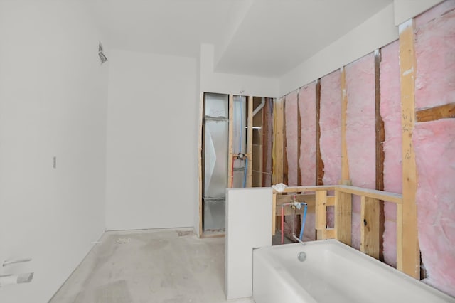 bathroom with concrete flooring and a bath to relax in