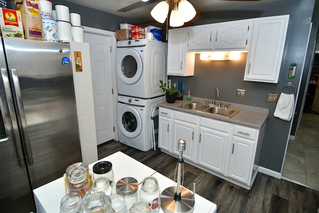 laundry area with ceiling fan, sink, stacked washer / dryer, and dark tile floors