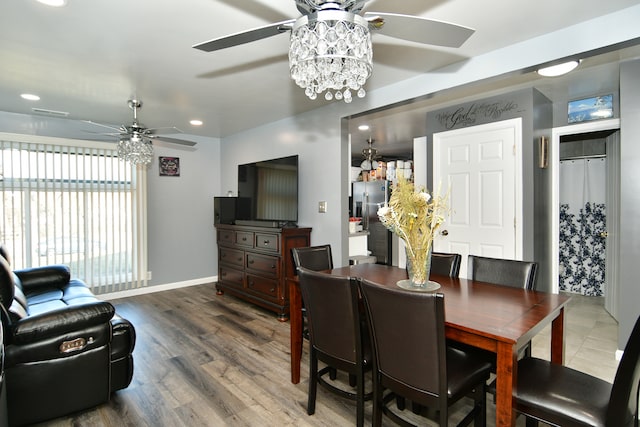 dining space with ceiling fan with notable chandelier and dark wood-type flooring