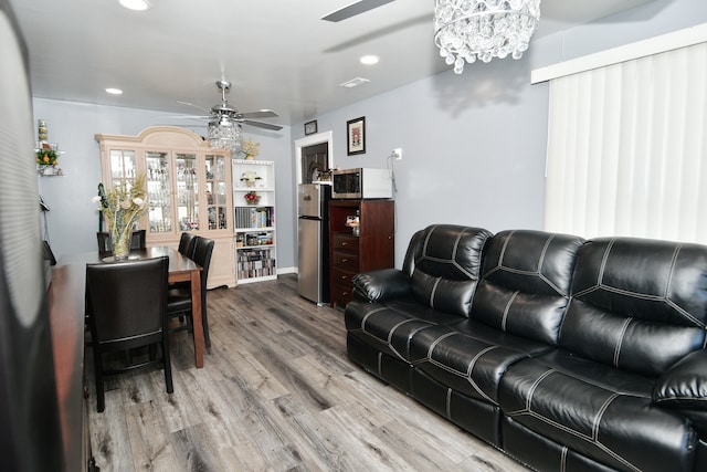 living room featuring light hardwood / wood-style floors and ceiling fan with notable chandelier