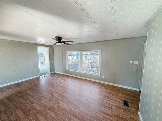 empty room featuring dark wood-type flooring, a textured ceiling, and ceiling fan