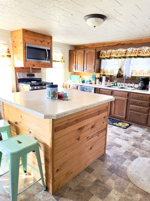 kitchen featuring dark tile flooring, appliances with stainless steel finishes, a healthy amount of sunlight, and sink